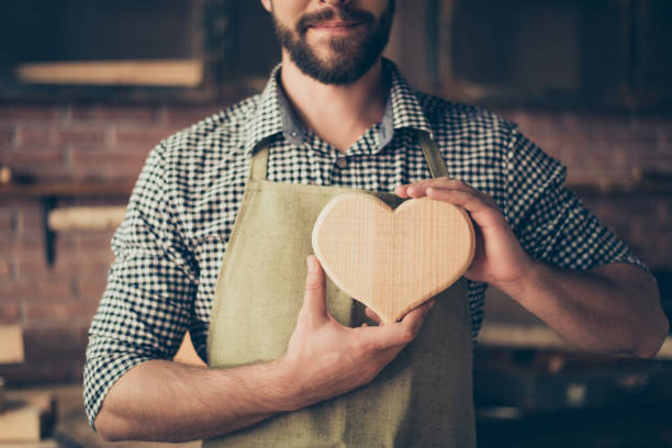 Male carpenter presenting a wooden heart sculpture